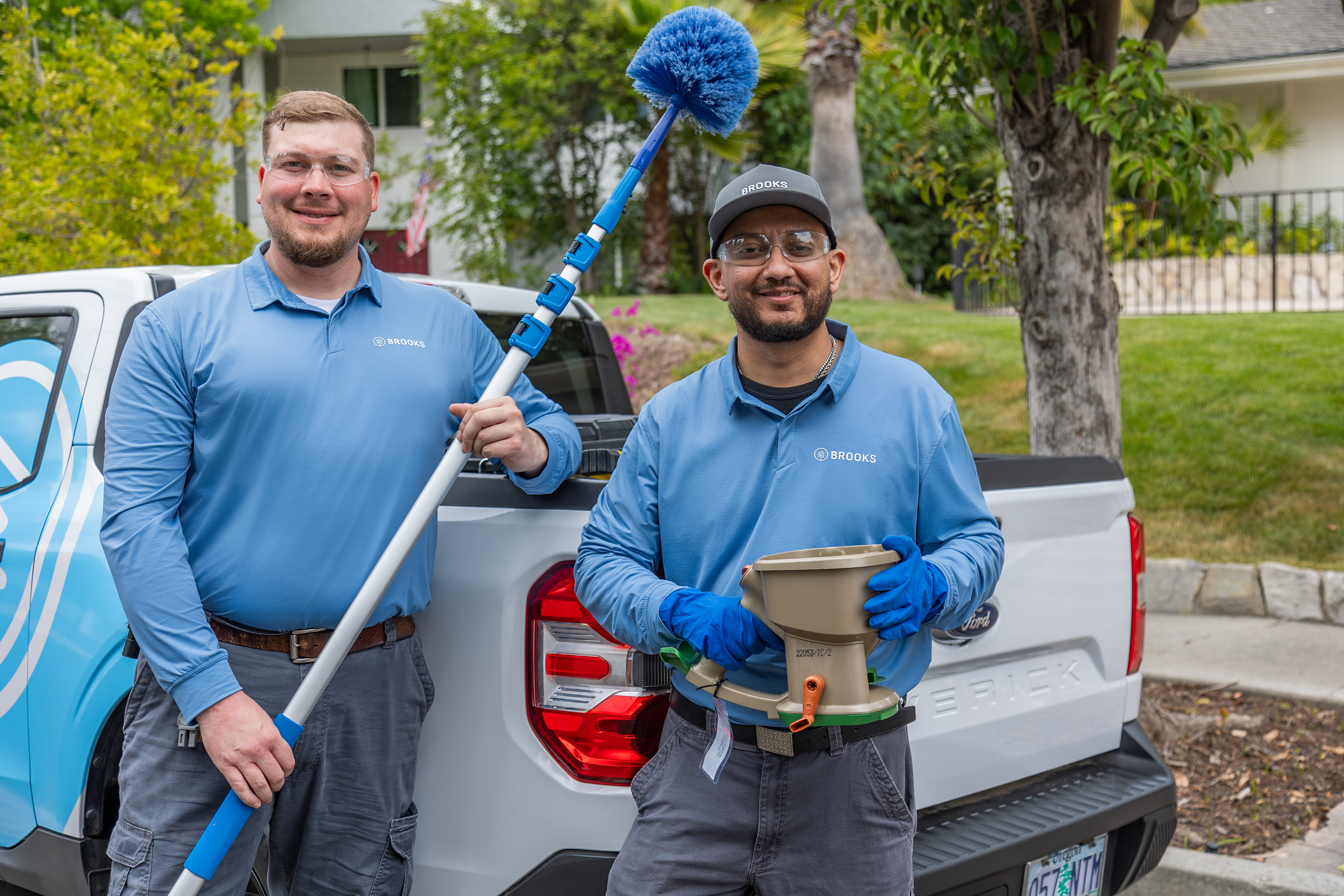 Two Brooks Pest Control technicians preparing equipment at truck